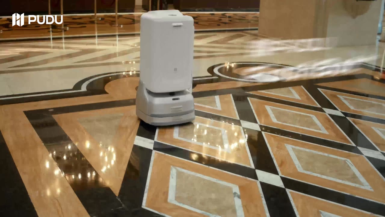 PUDU FlashBot Max enclosed delivery robot moving through a hotel corridor toward an elevator